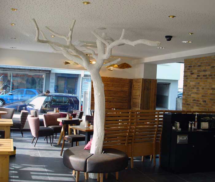 Kahler Kunstbaum (weiß) mit flacher Krone in einem Cafe