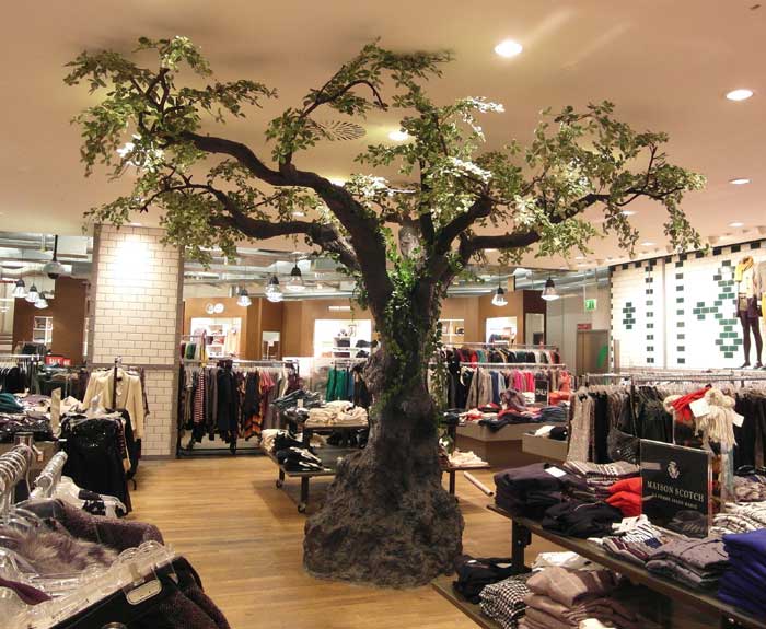 Großer Kunstbaum (Olive) mit knorrigem Stamm in einem Modehaus